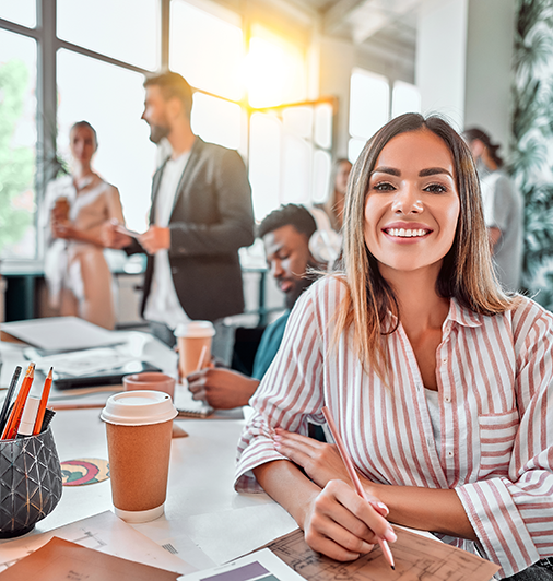 Smiley lady looking to camera with busy office environment behind her